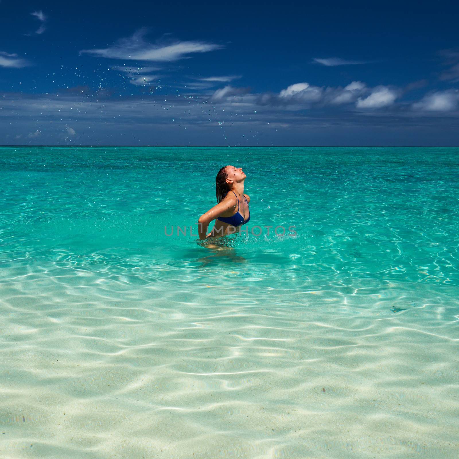 Woman splashing water with her hair in the ocean