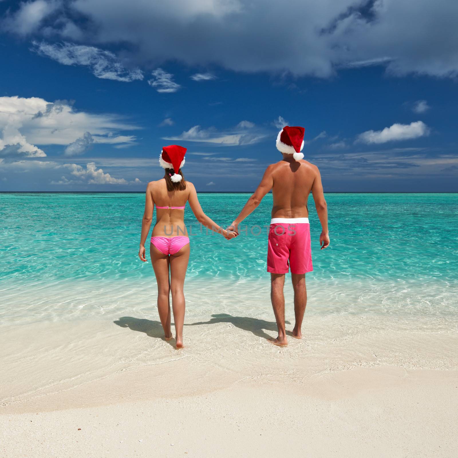 Couple in santa's hat on a tropical beach at Maldives