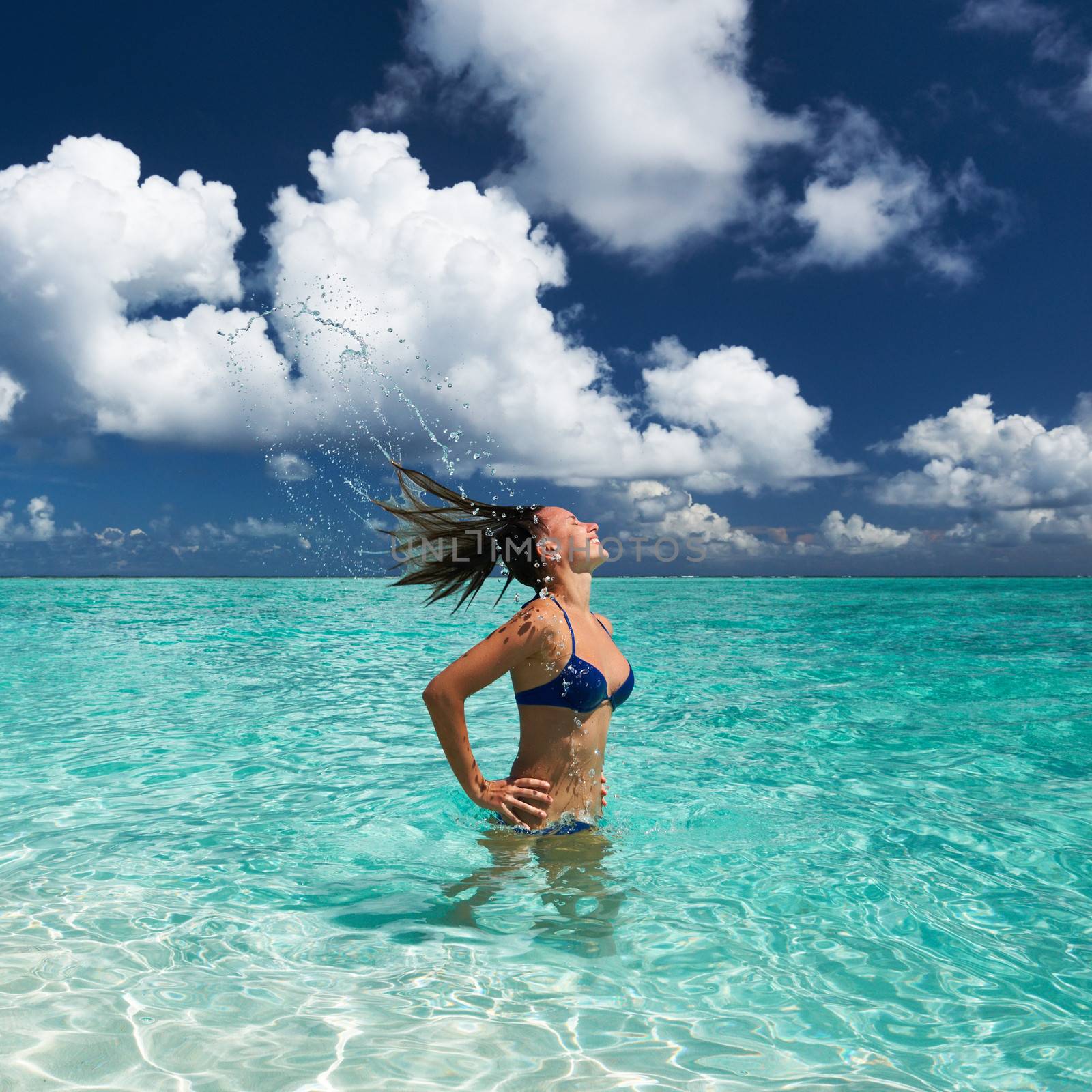 Woman splashing water with hair in the ocean by haveseen