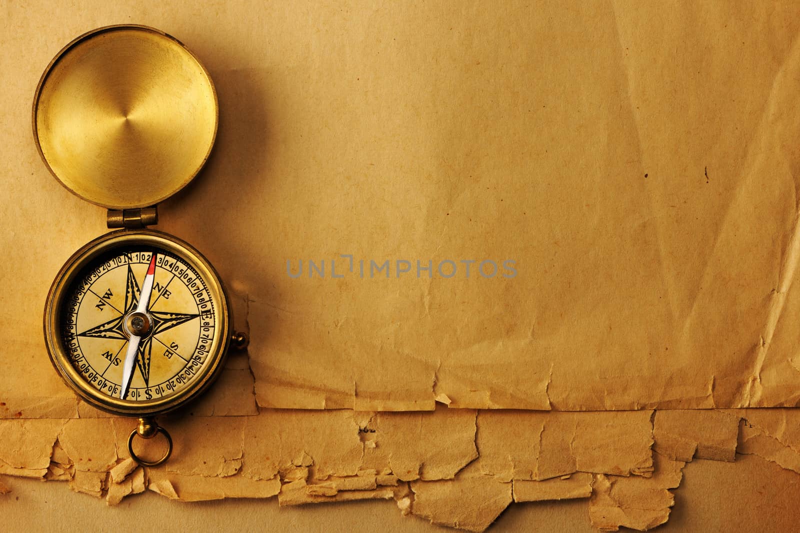 Antique brass compass over old paper background