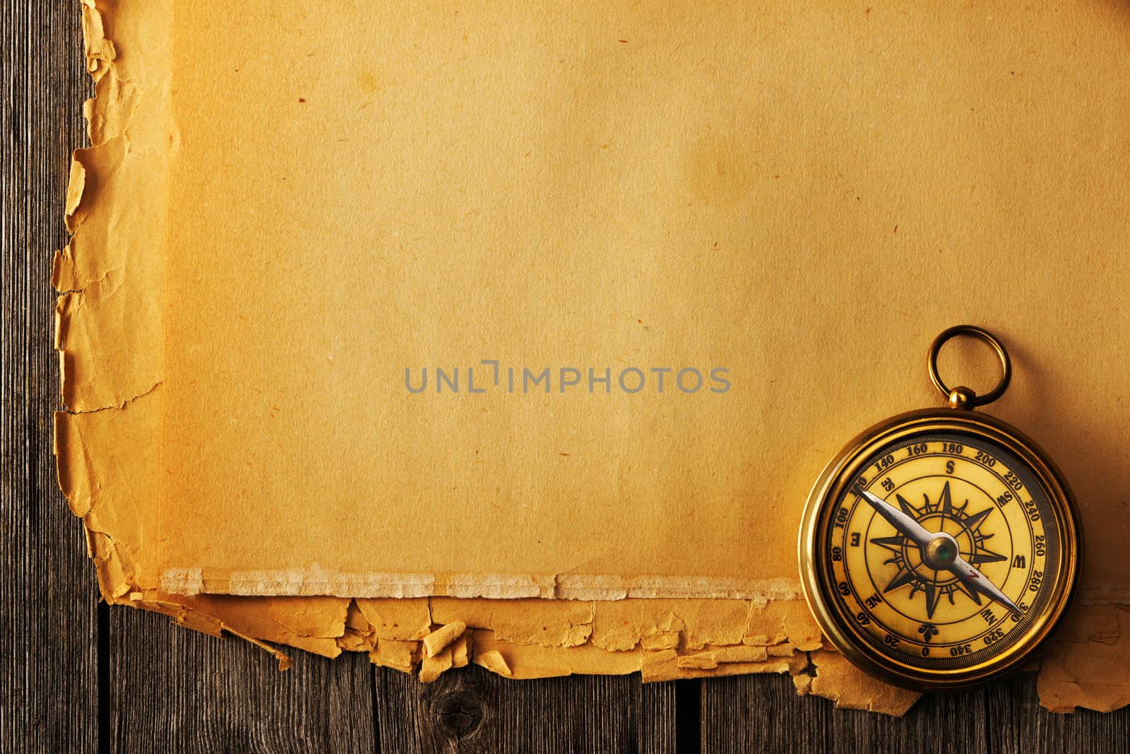 Antique brass compass over old paper background