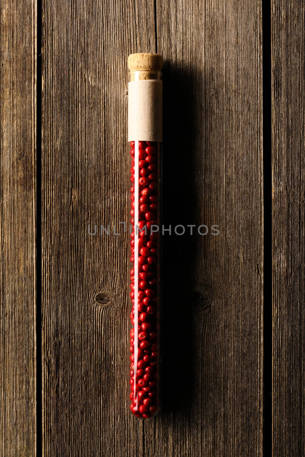 Rose pepper in beaker on wooden table by haveseen