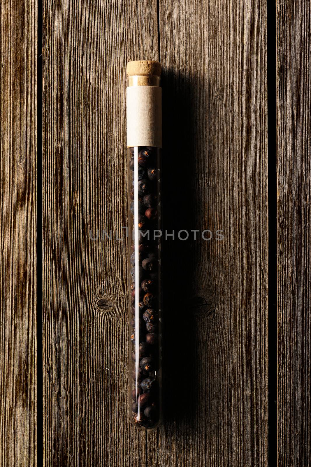 Juniper berries in beaker on wooden background