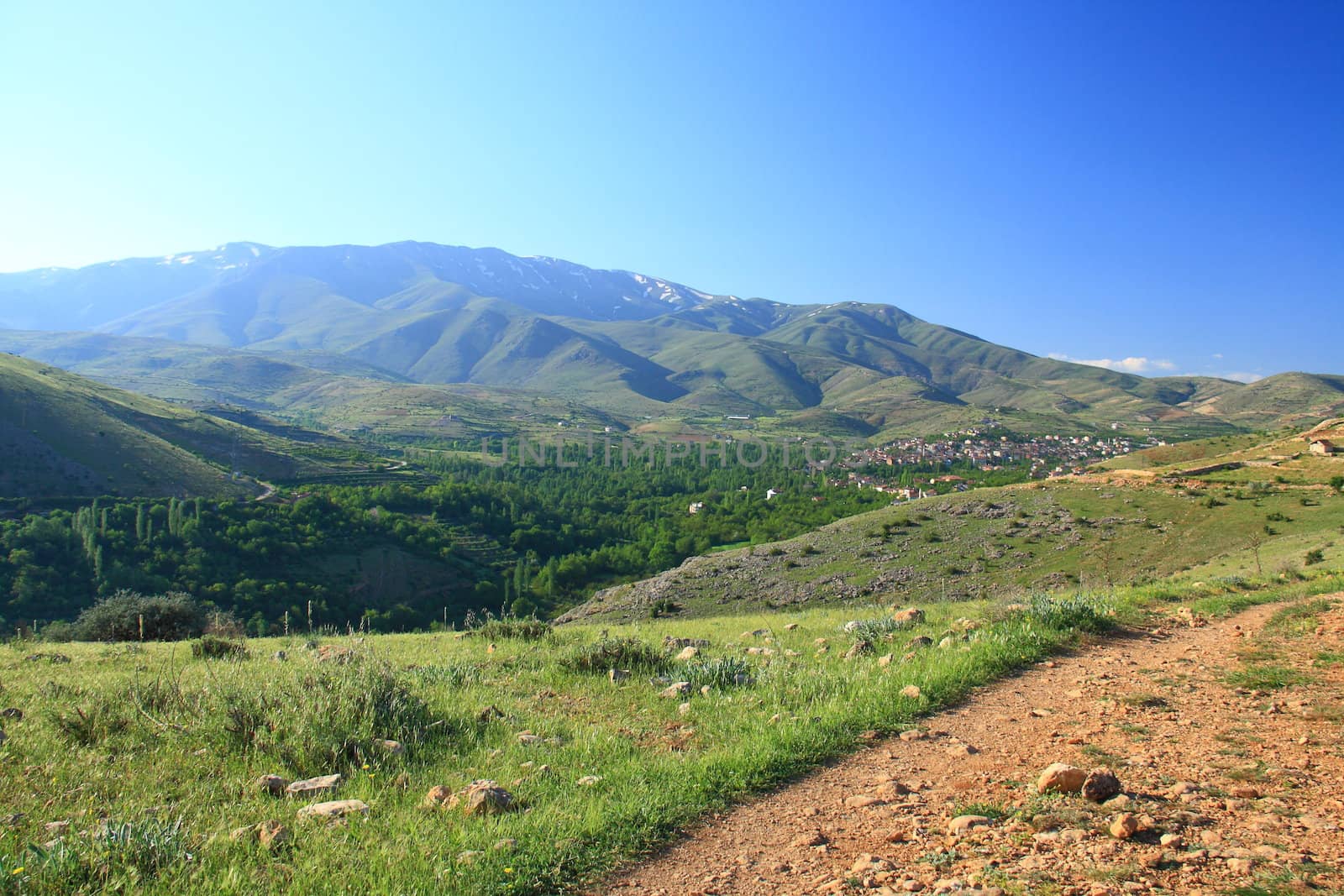 village between hills on spring day with blue sky