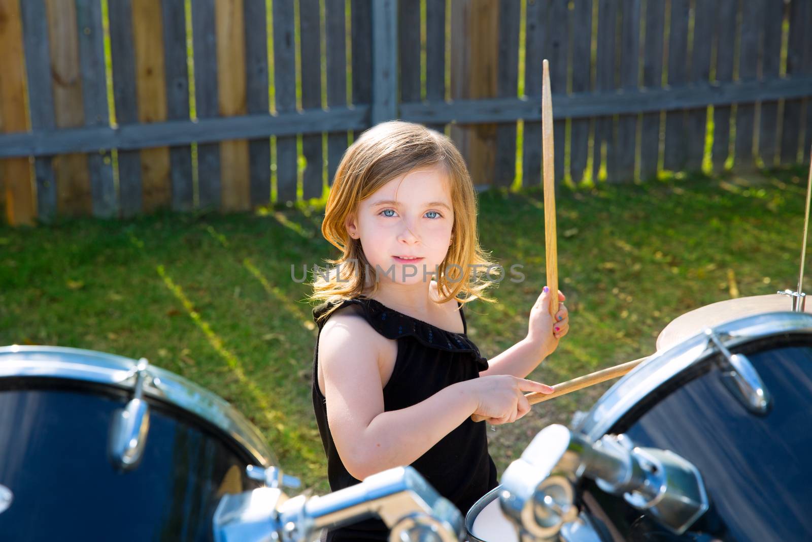 Drummer blond kid girl playing drums in tha backyard by lunamarina