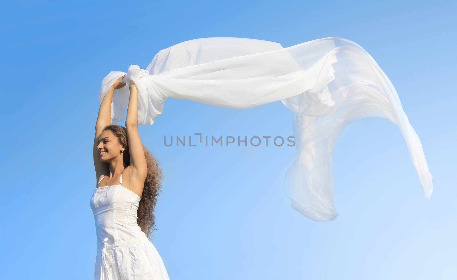 Portrait of a young woman wearing dress holding white fabric outdoors