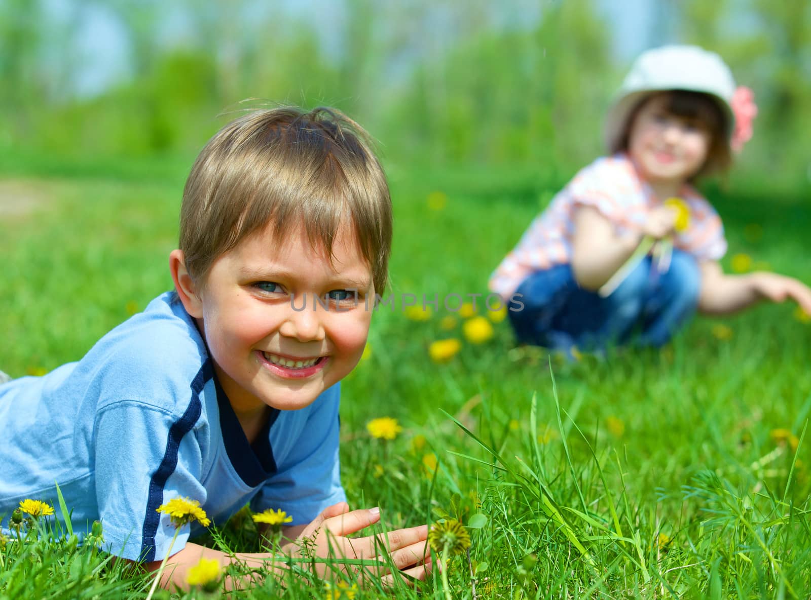 Sweet beautiful girl sitting on a green meadow with dandelions