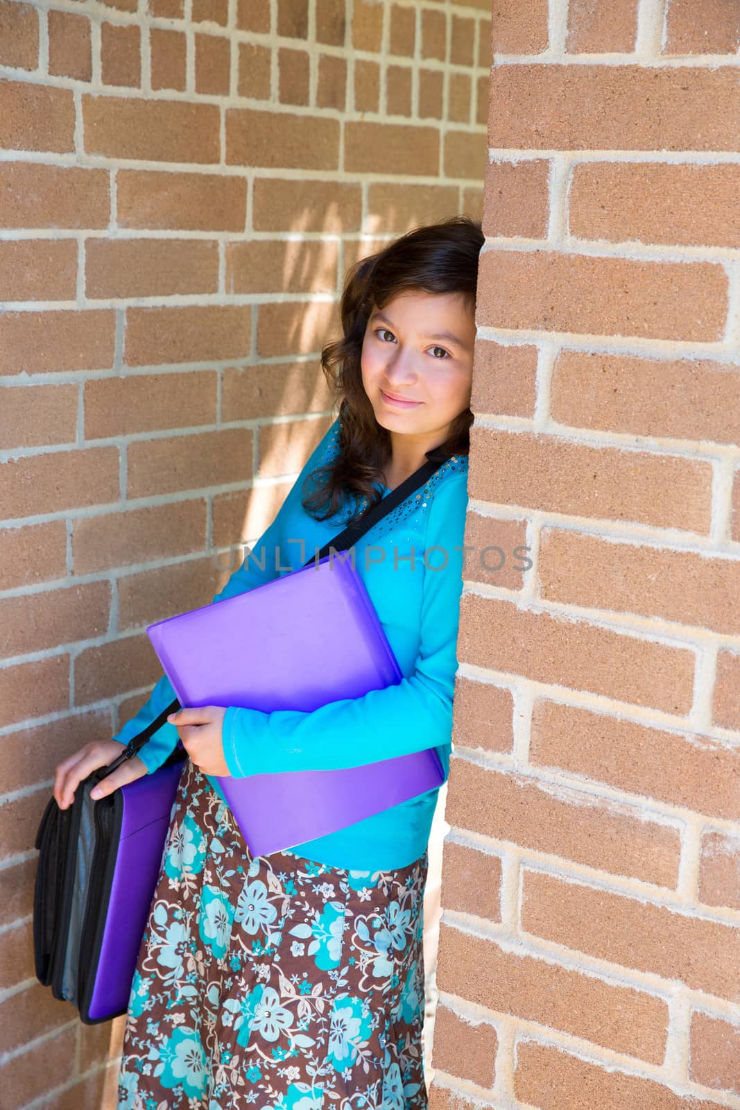 Schoolgirl teenager at school brick wall happy with folder and bag