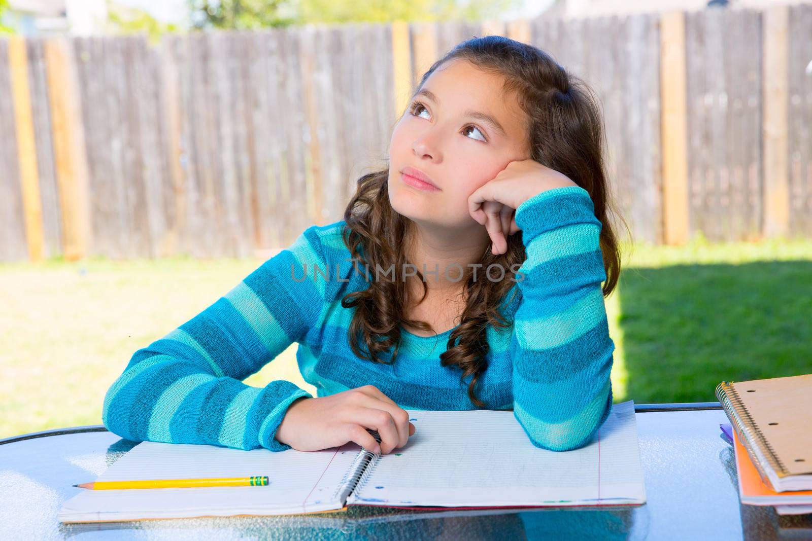 American latin teen girl relaxed on table doing homework on backyard