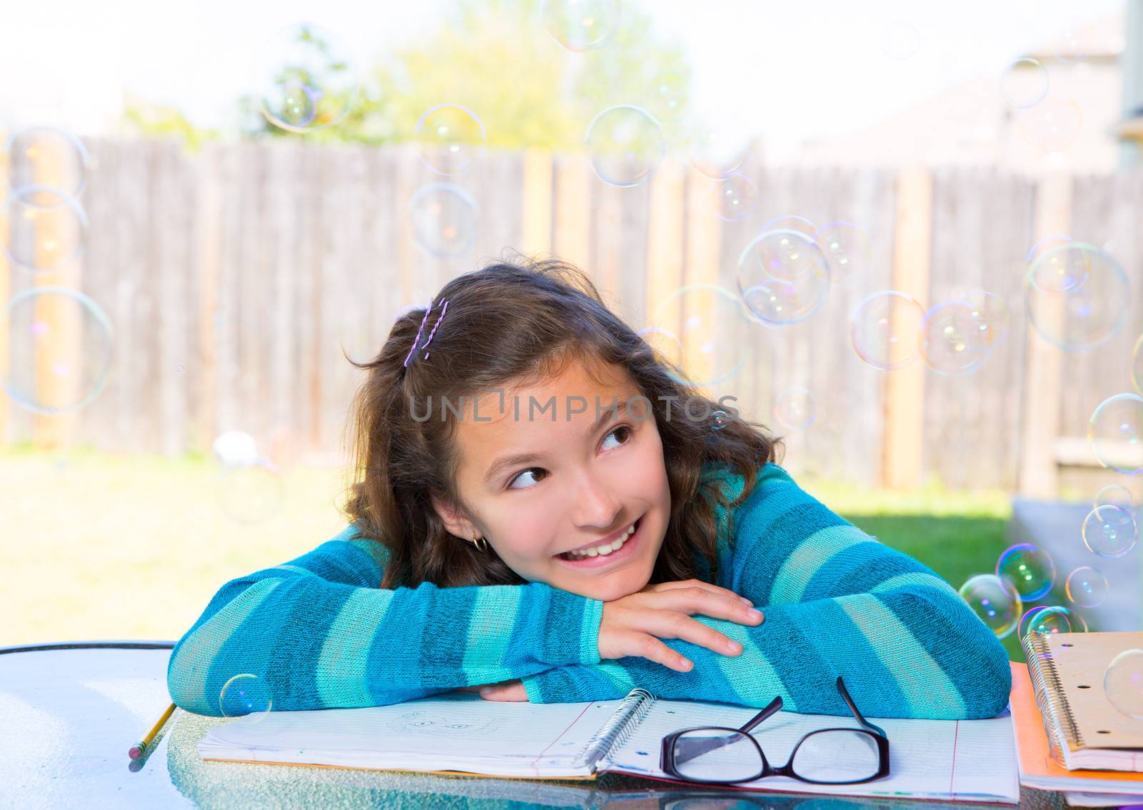 American latin teen girl with soap bubbles doing homework on backyard