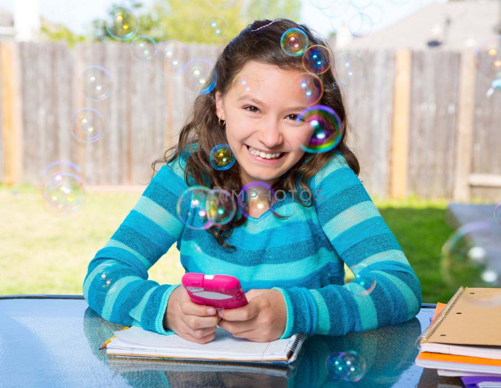 American latin teen girl with smartphone doing homework on backyard