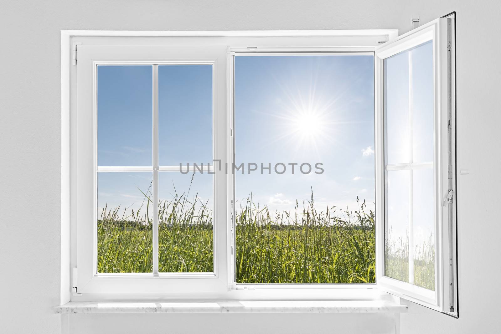 picture of a white wall with white half open window indoor and outside green meadow with sun and blue sky