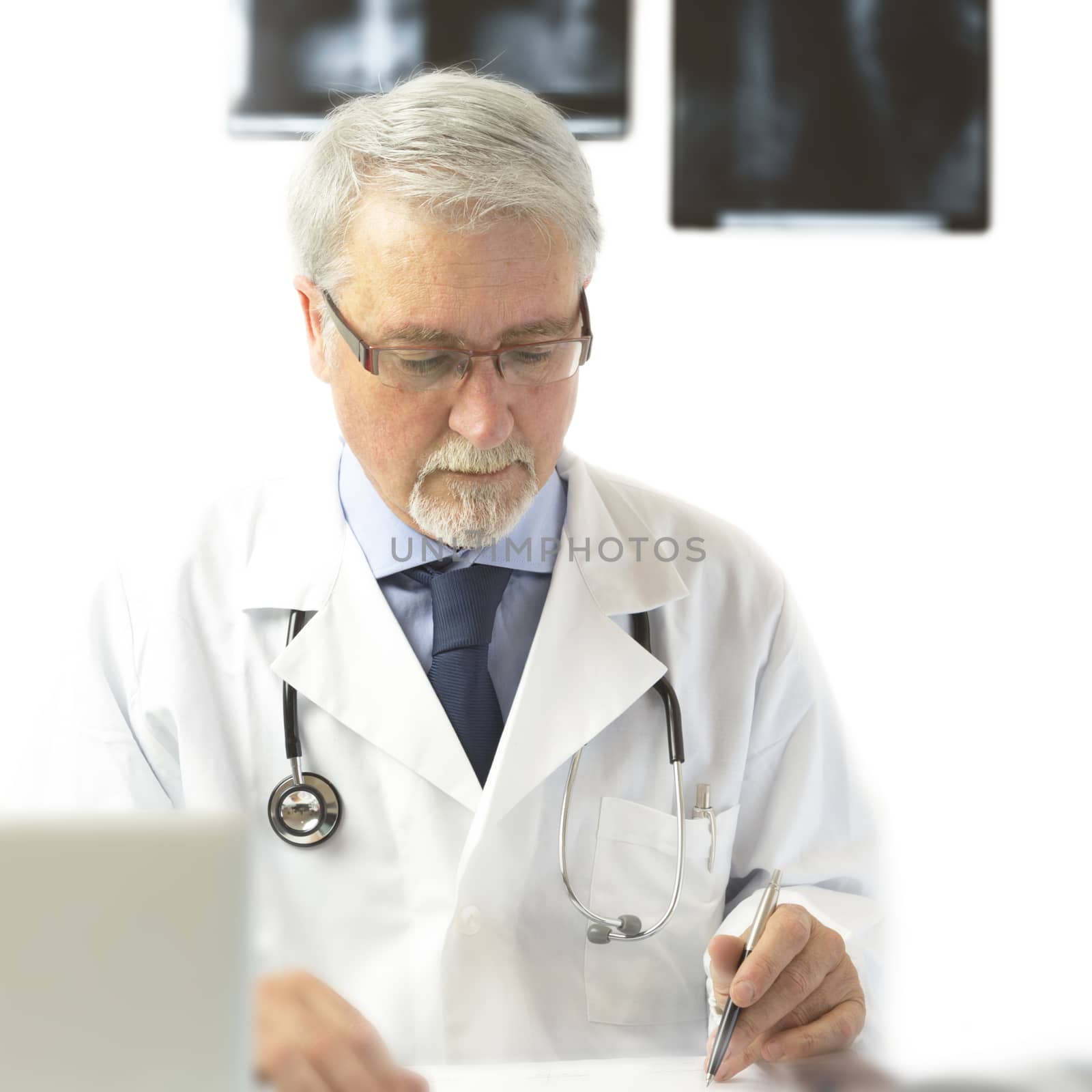 Doctor with scrubs and stethoscope writing a prescription, on the white background with x-rays.