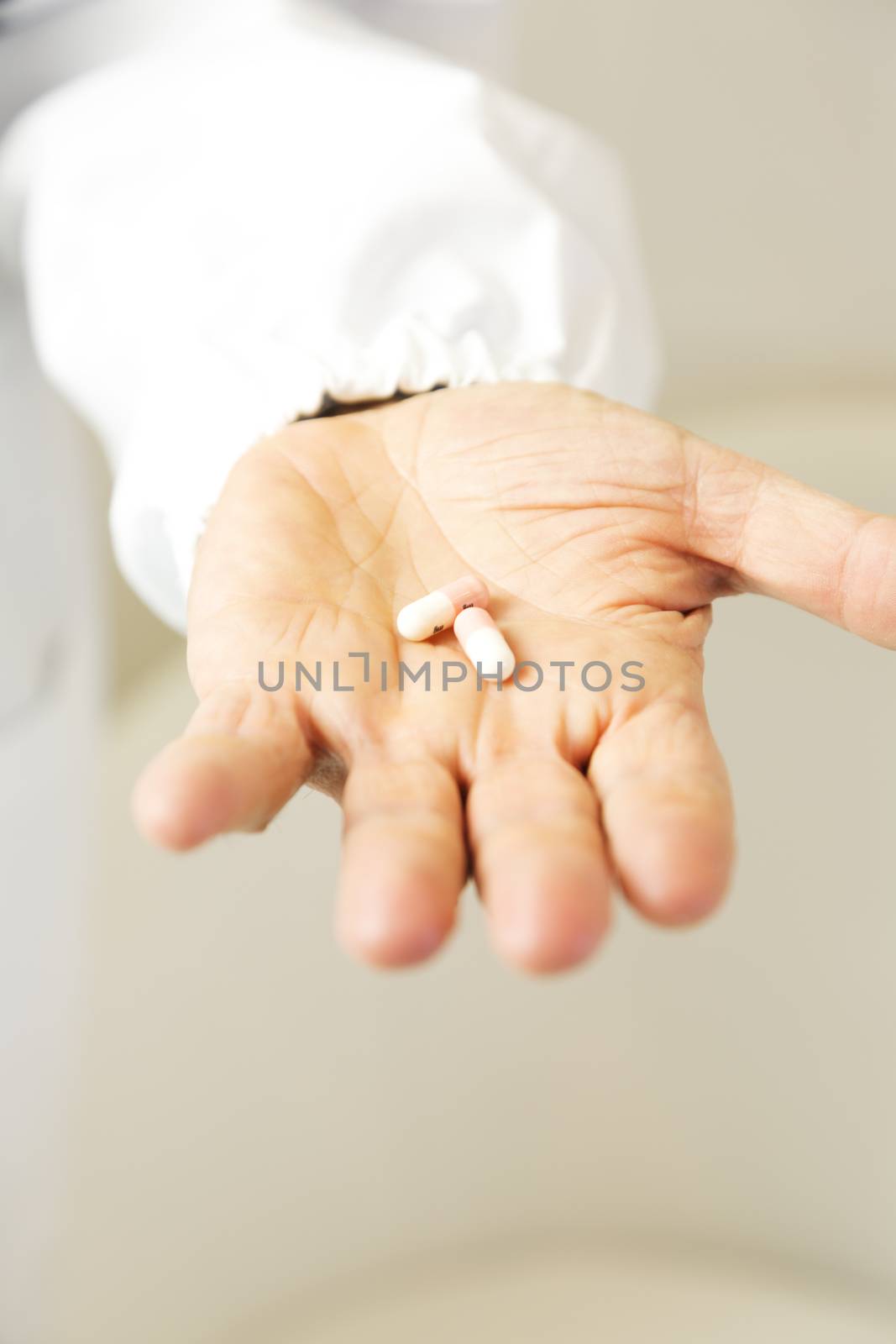 Doctor holding white and pink pills against anxiety on light gray background