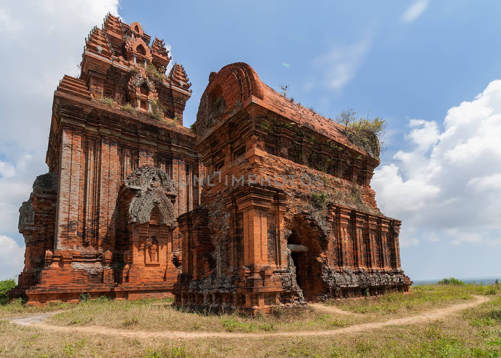 Vietnam, two impressive Banh It Cham towers on the green hill against the blue sky.