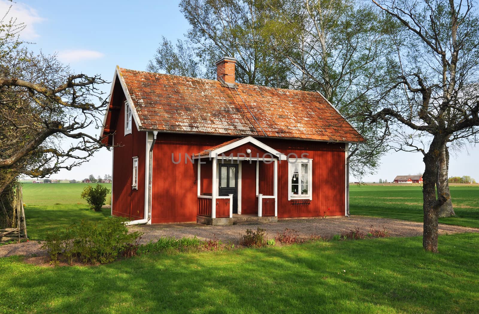 Old red cottage surrounded by farmland.