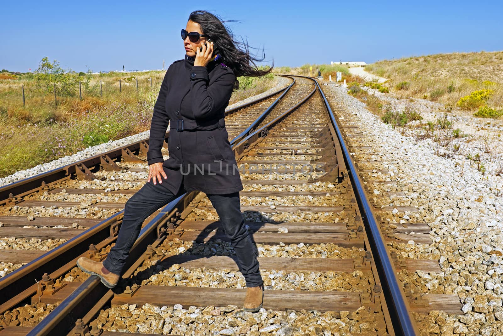 Woman making a phone call at a railroad track by devy