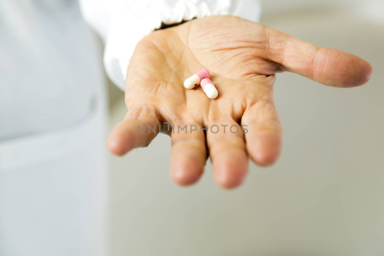 Doctor holding white and pink pills against anxiety on light gray background