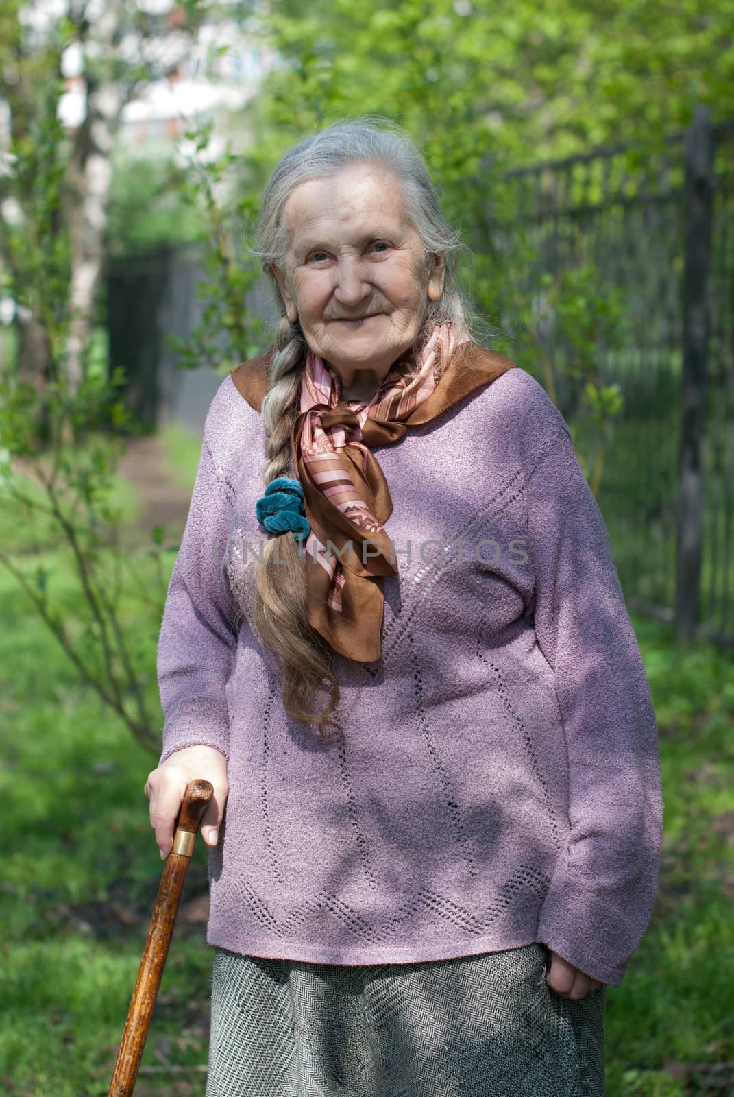 old grandmother with a long braid in the summer in the garden
