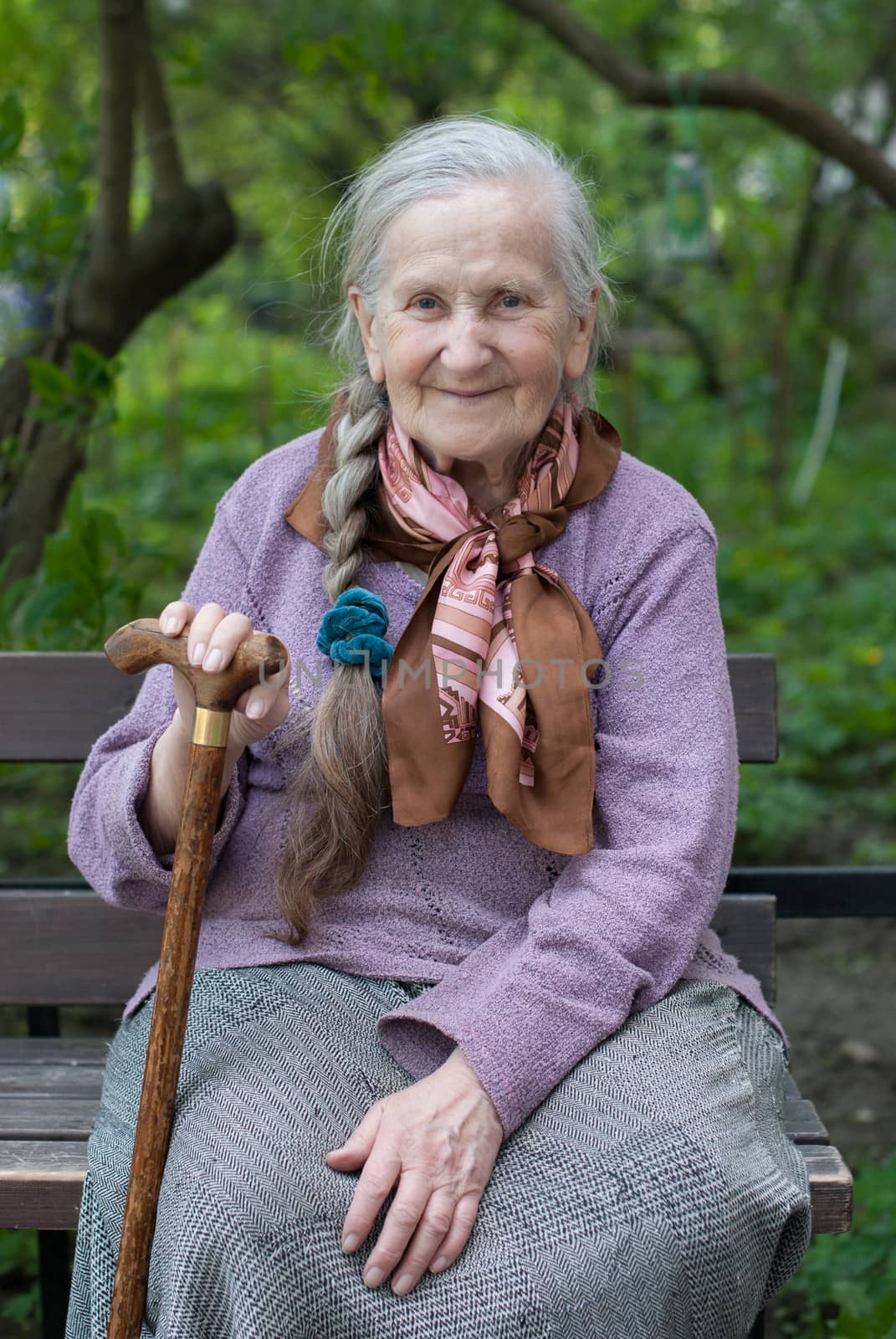 old grandmother with a long braid in the summer in the garden