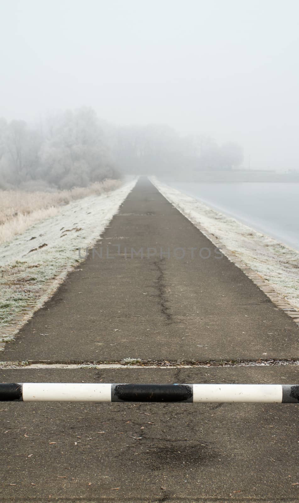 road to far away with barrier on freeze hoarfrosted landscape