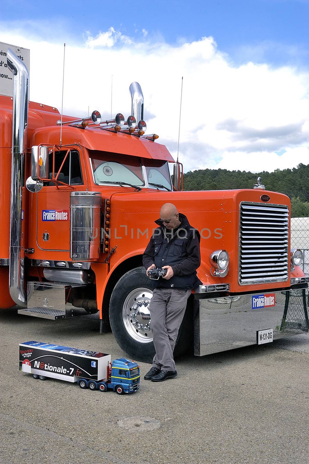 lorry driver having fun with a small truck radiocontrolled in front of its enormous truck