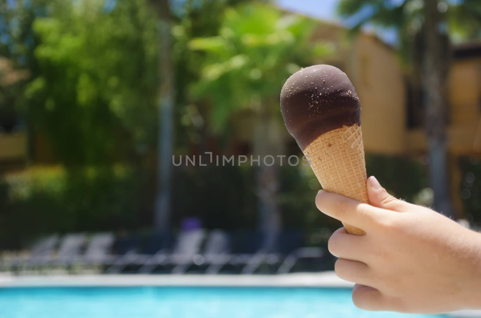 Ice cream in a child's hand close-up on the background of the swimming pool