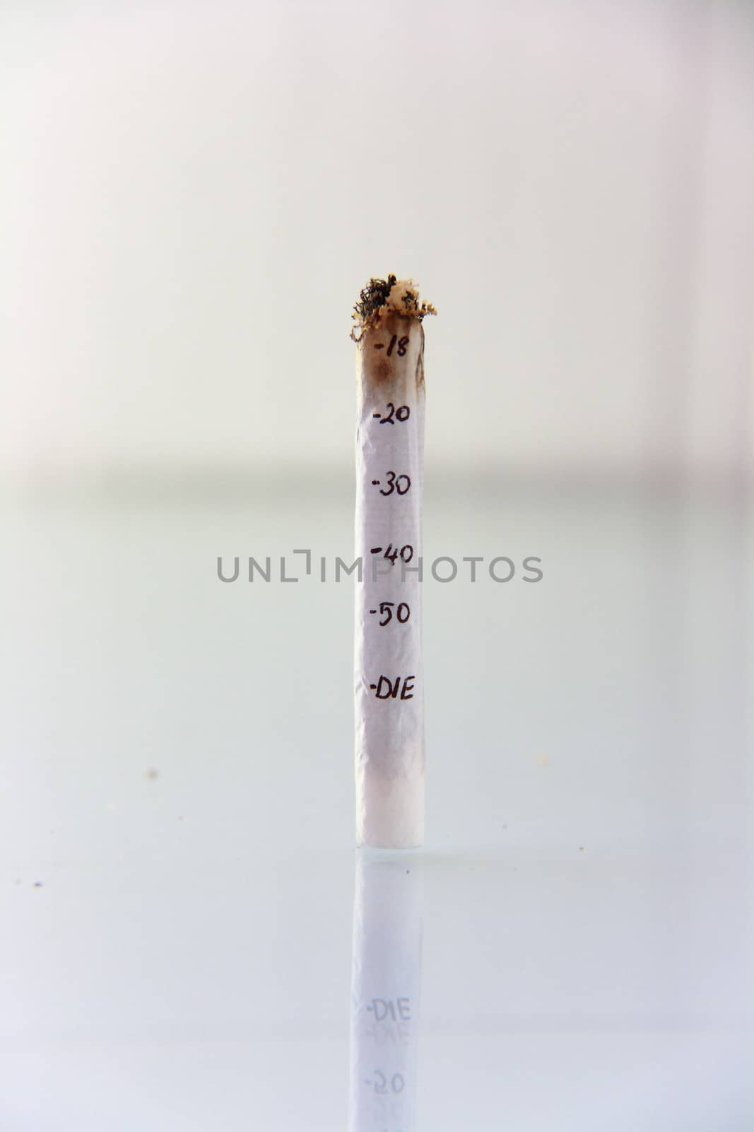 hand made cigarette burning in front of white background