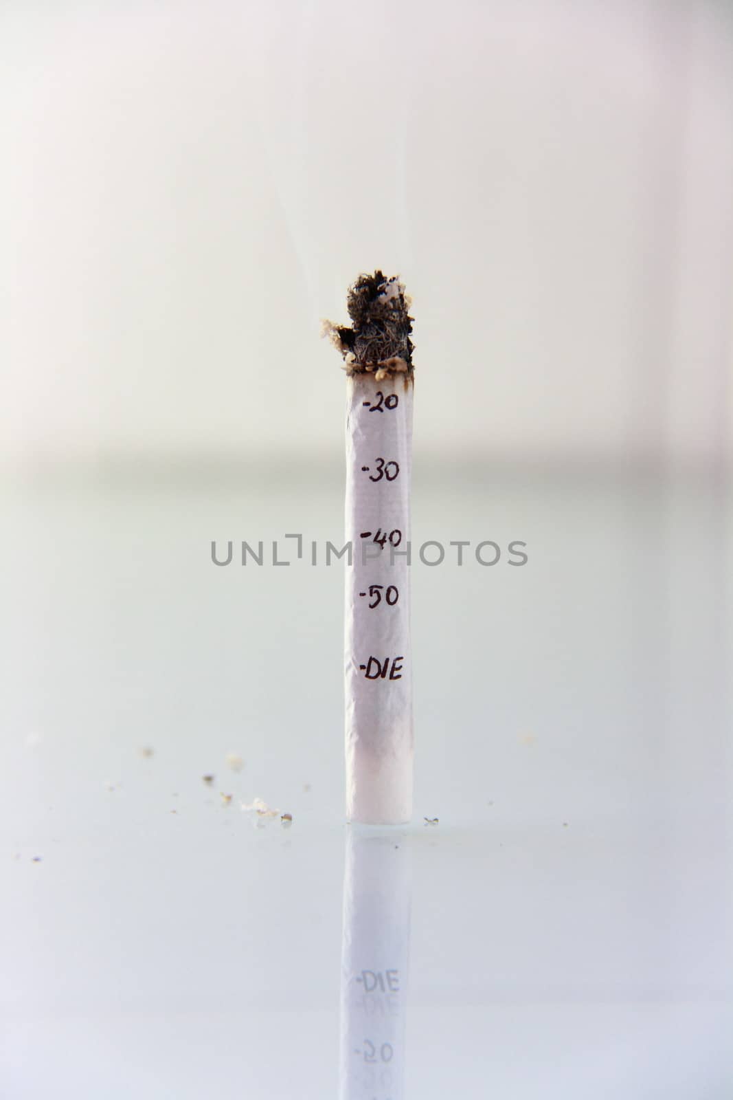 hand made cigarette burning in front of white background
