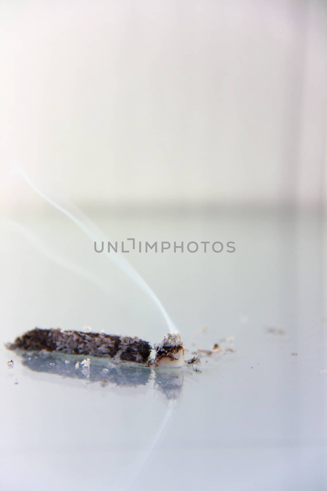 hand made cigarette burning in front of white background