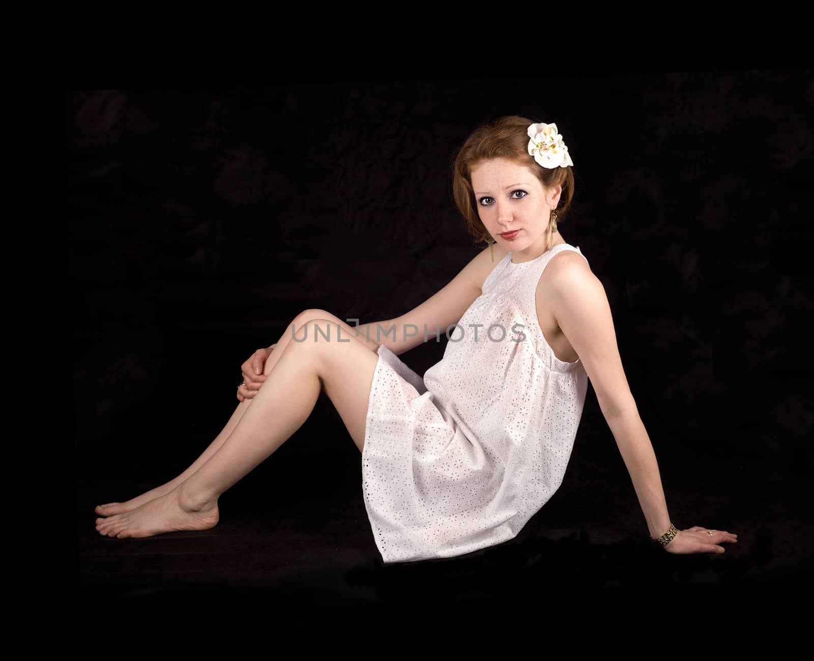 The girl with red hair and freckles in a white dress on a black background