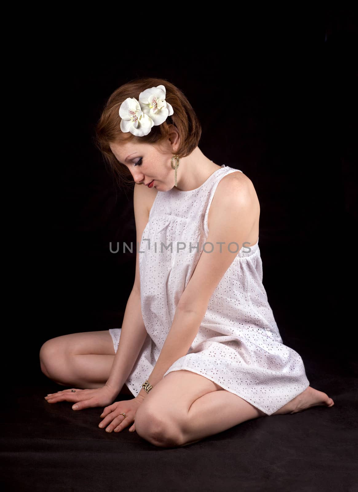 Red-haired girl with ornaments in white dress on a black background