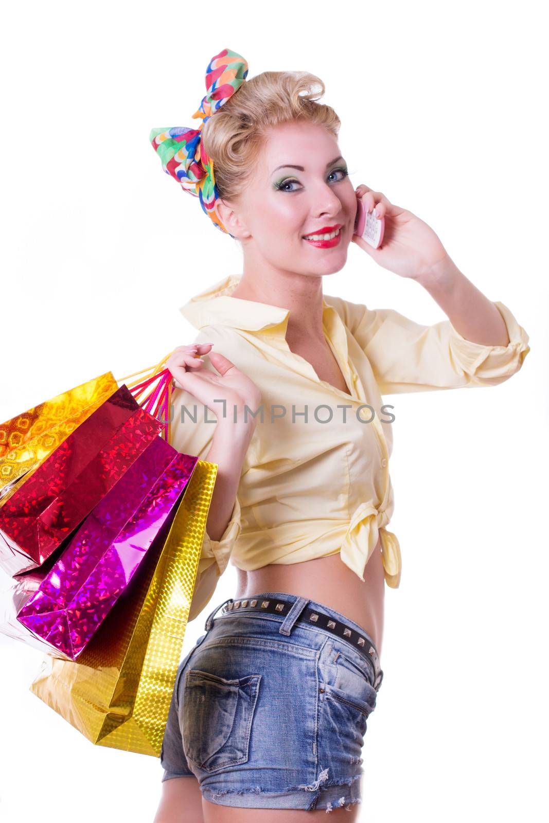 Cheerful pinup woman with shopping bags and phone isolated on white
