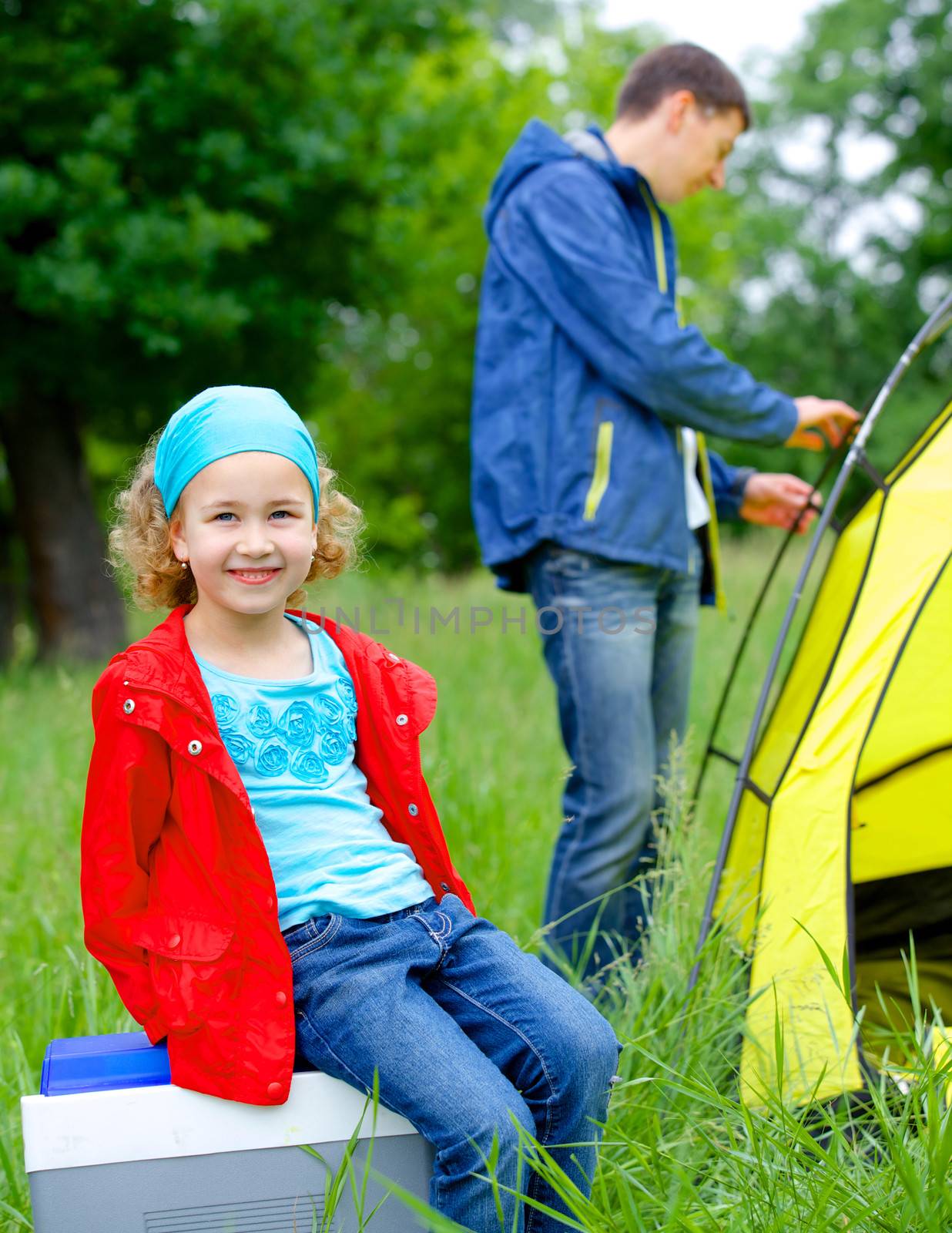 Young girl with her father near tent in camping on the nature