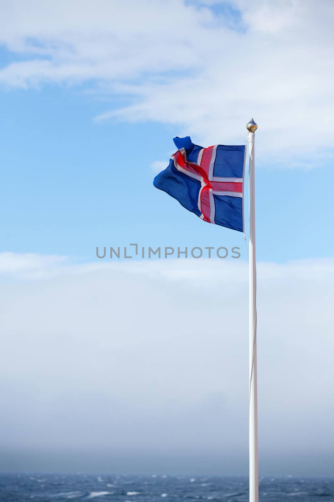 The flag of Iceland waving in the wind on a background of a stormy sky. Vertical view