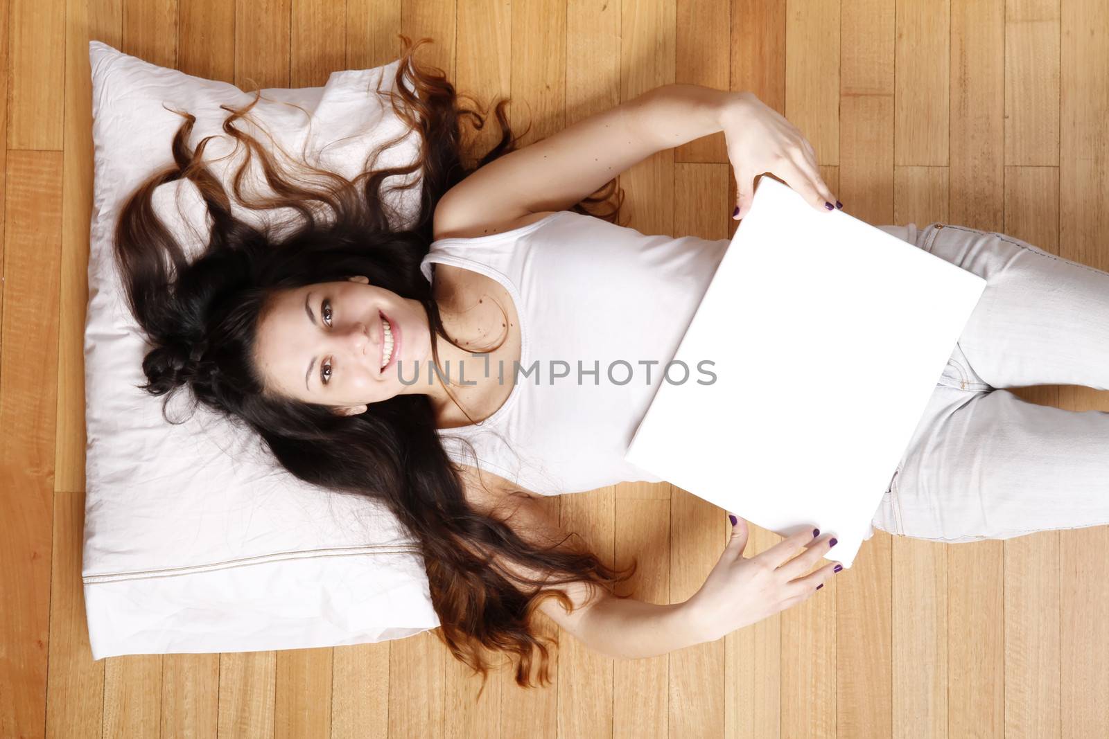 A young adult woman lying on the floor with a blank canvas.