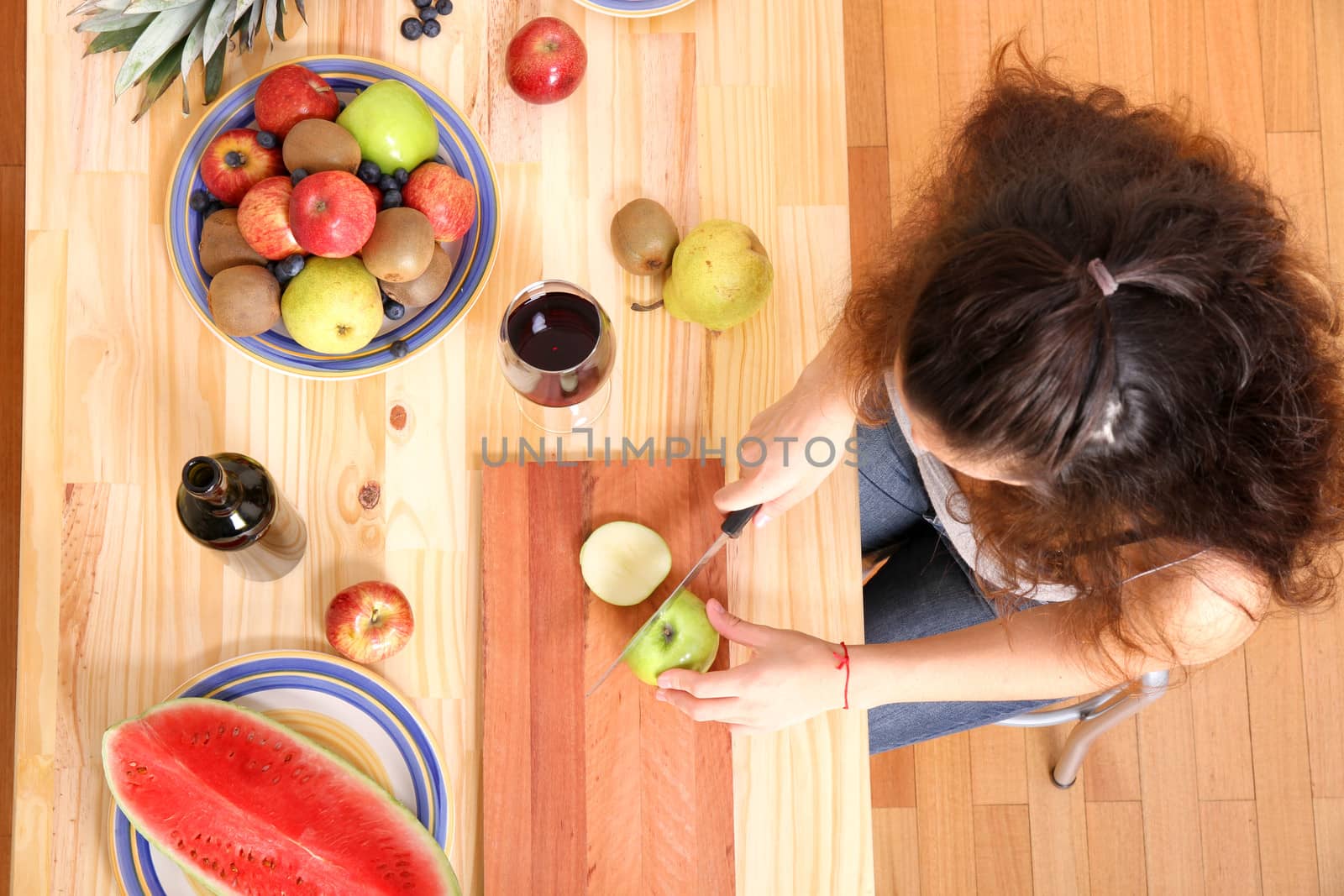 A young adult woman cutting fruits in the kitchen.