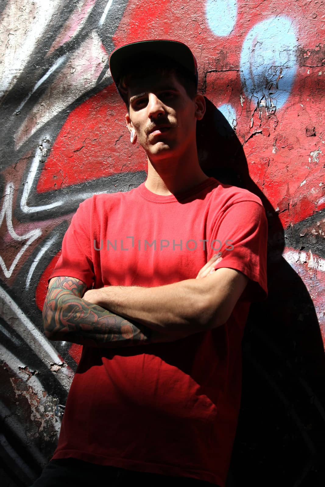 A young Rapper leaning against a wall.