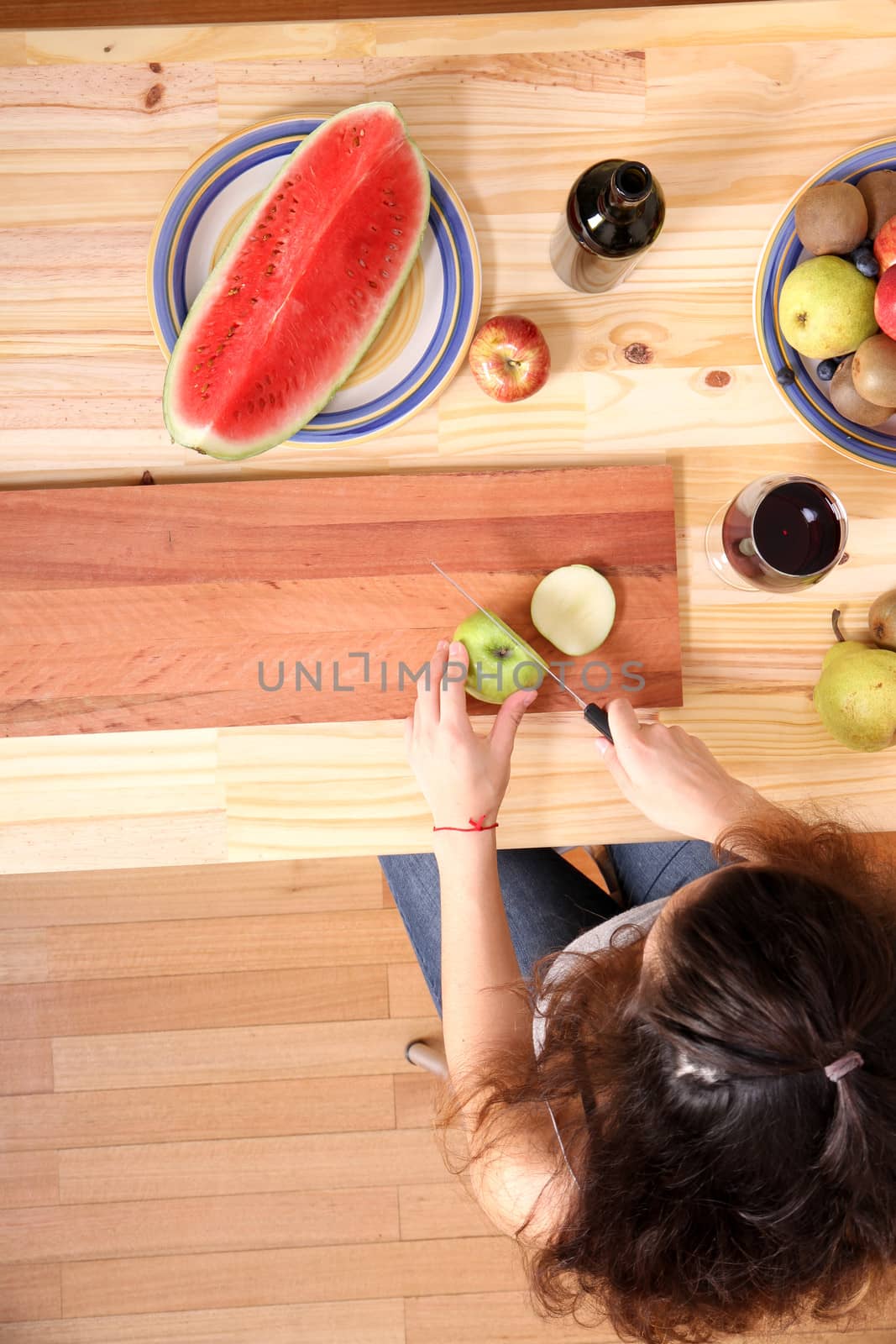 A young adult woman cutting fruits in the kitchen.