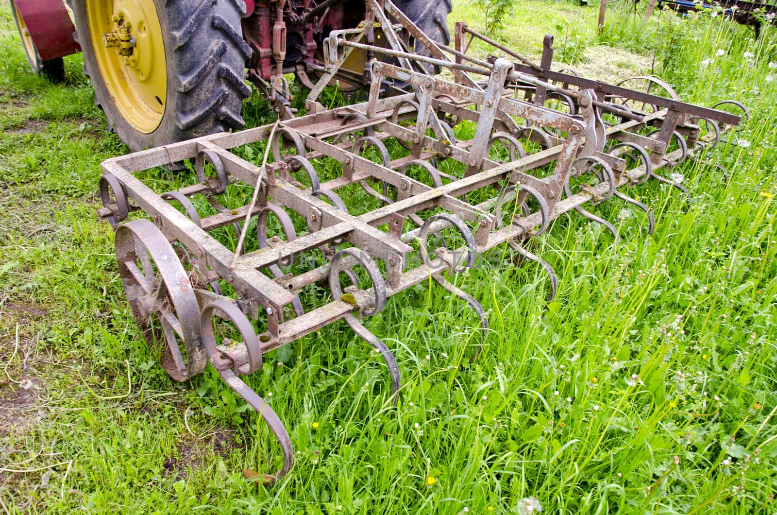 tractor on farm field gras with old metal harrow