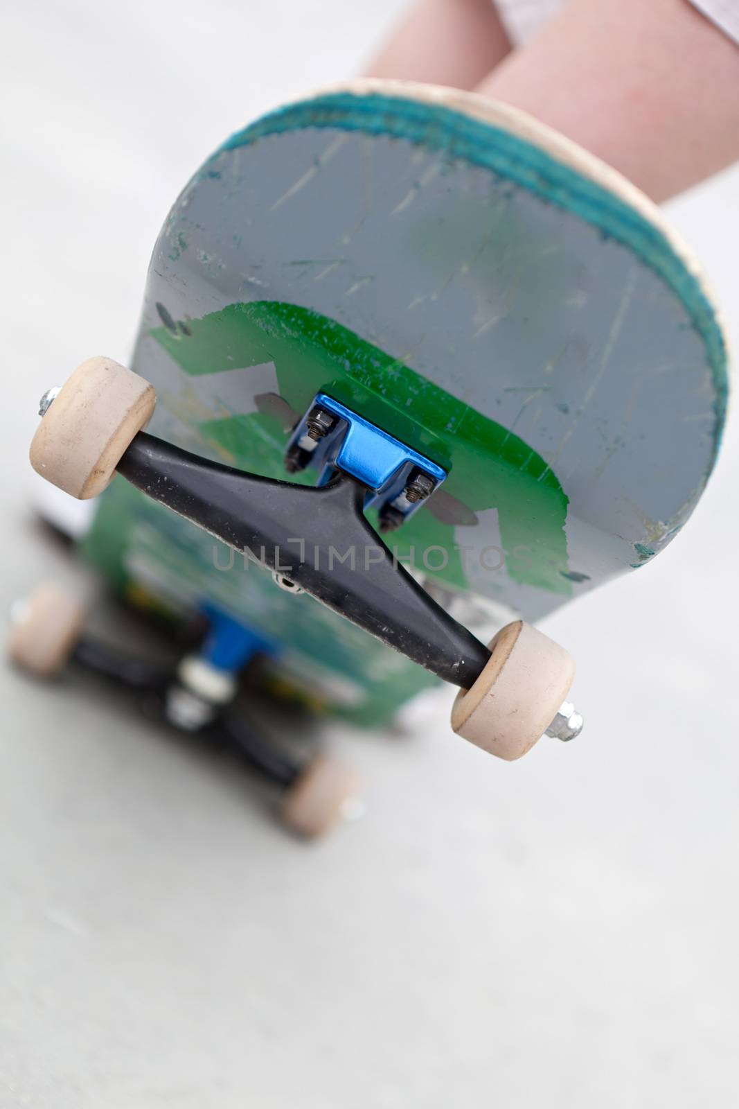 Close up of a skateboard popped up showing the front trucks and wheels. Shallow depth of field.