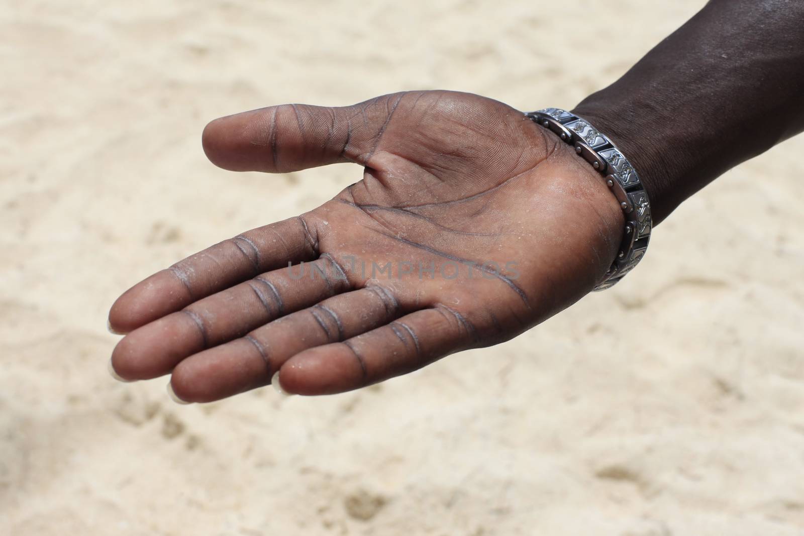 Open hand of the black man on a background of sand