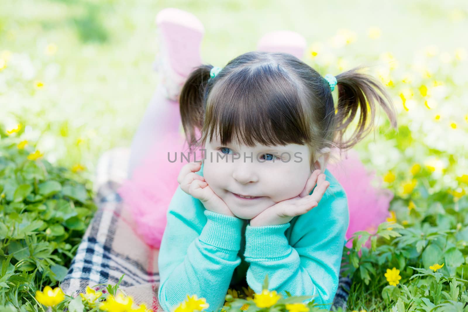 Portrait of the girl lying on a glade with dandelions