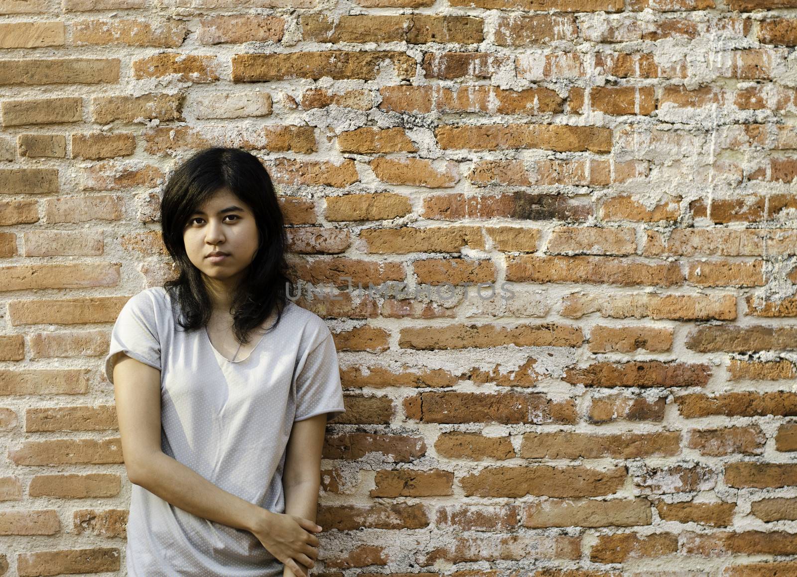 Young Asian woman against a Brick Wall with Copy Space. 