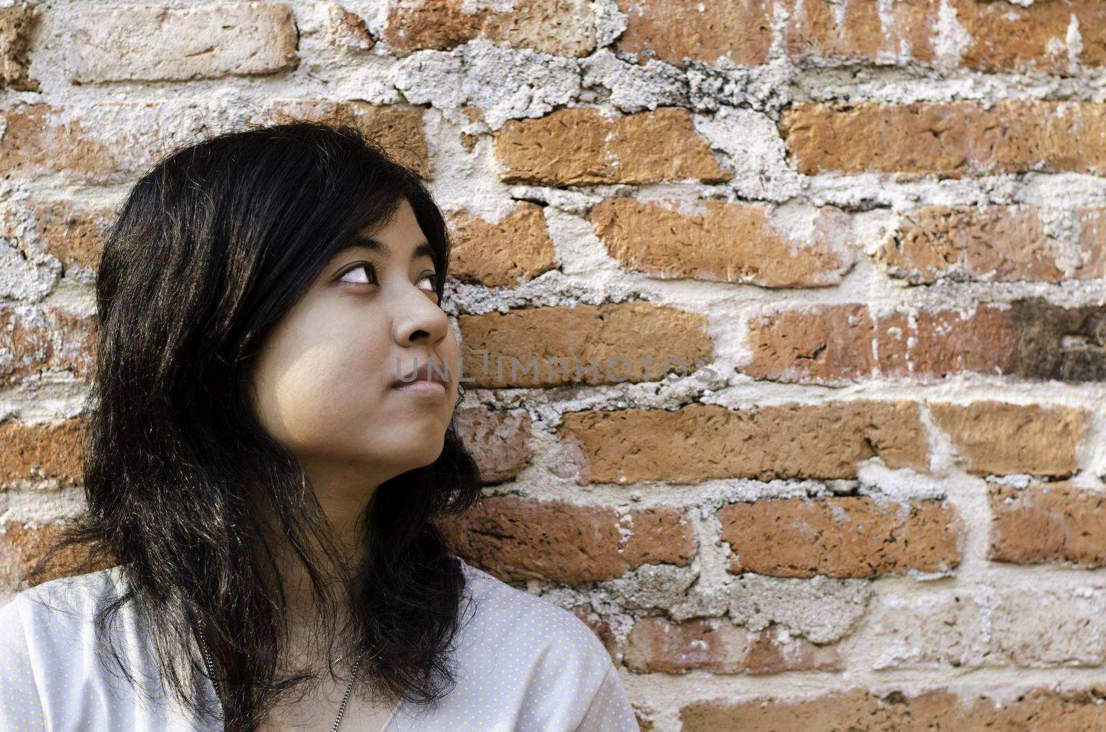 Petty young brunette woman against a Brick Wall with Plenty of Copy Space. 