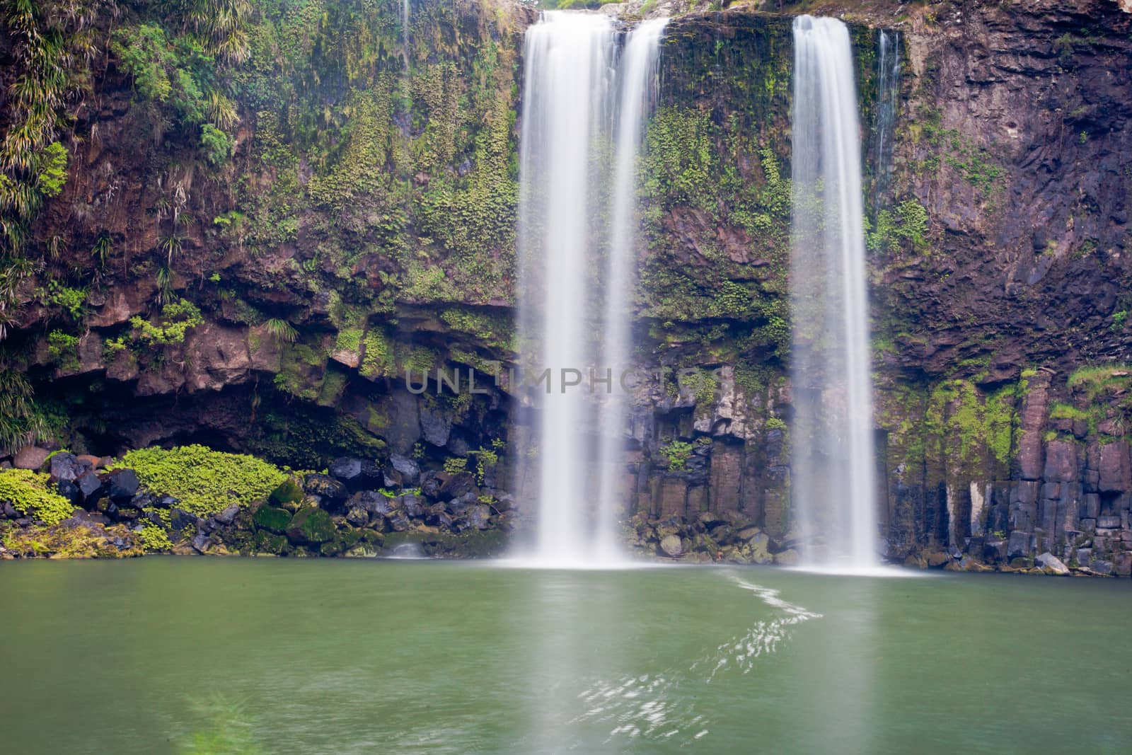 Waterfall cascading over rocky cliff into peaceful refreshing fresh water pool