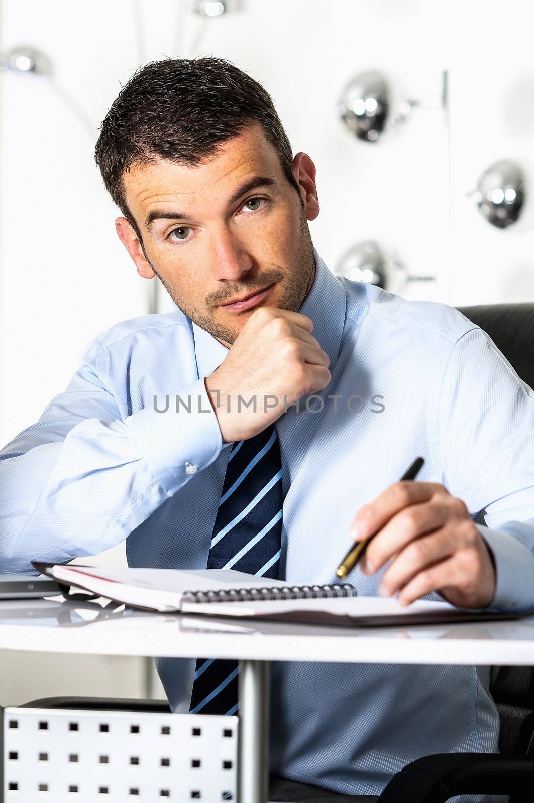 An attractive business man is writing on a paper