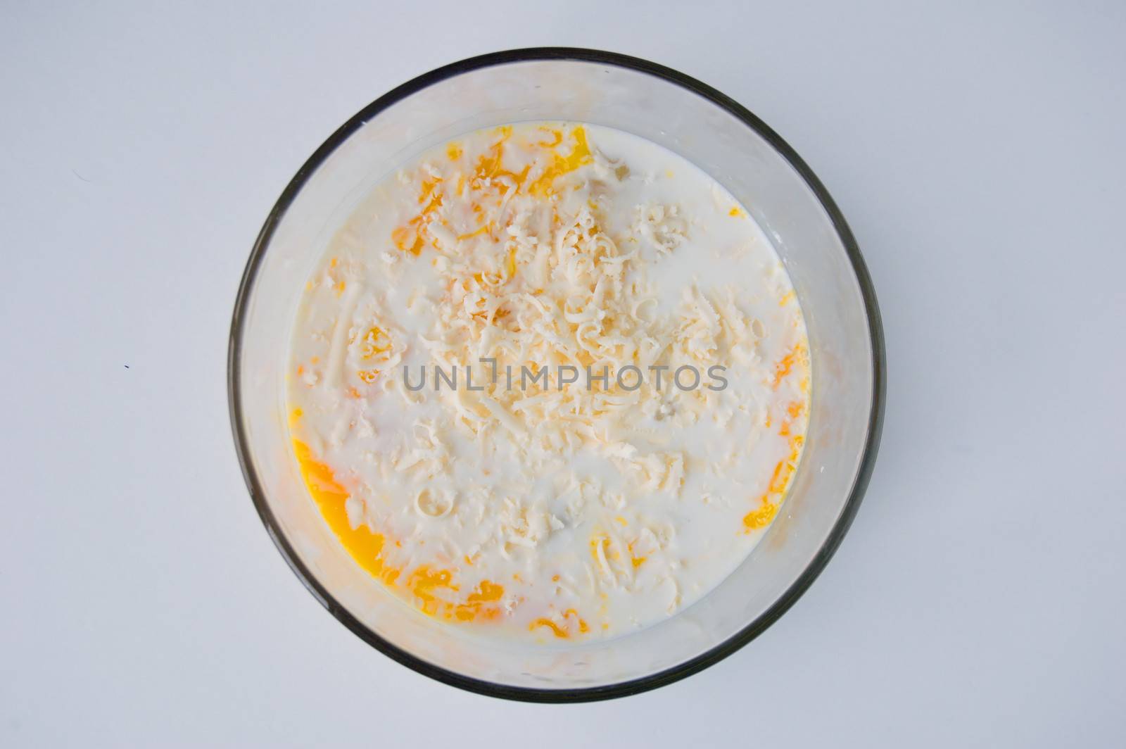 Mix of Raw eggs and milk in glass bowl.