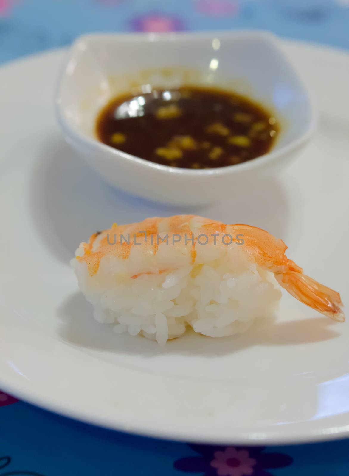 sushi  with tiger shrimp on white plate served with sauce 