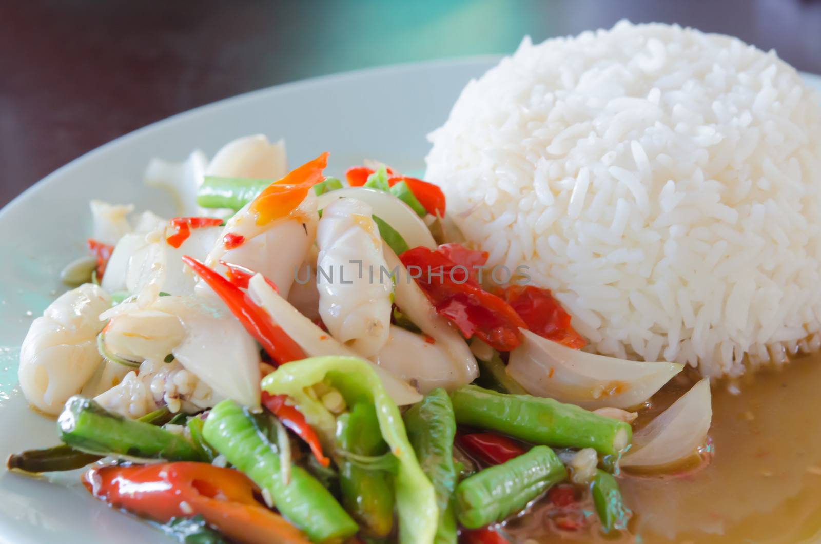 close up squid  fried with chili pepper and mix vegetable served with steamed  rice on dish